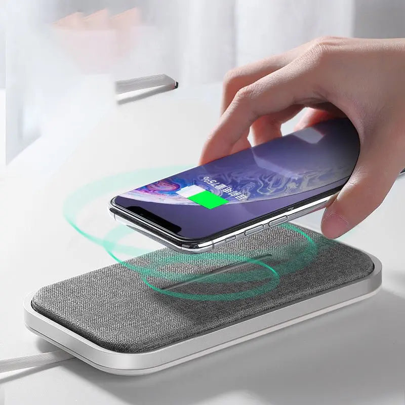 Hand placing smartphone on grey fabric wireless charger showing fast charging icon on screen