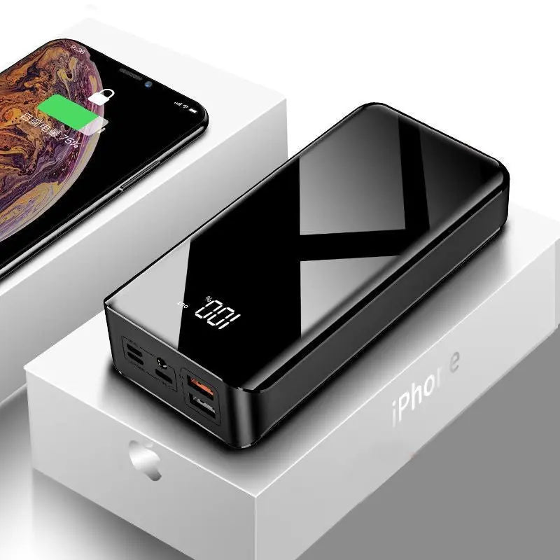 Glossy black 30000mAh power bank with digital display on white iPhone packaging and smartphone nearby charging icon visible