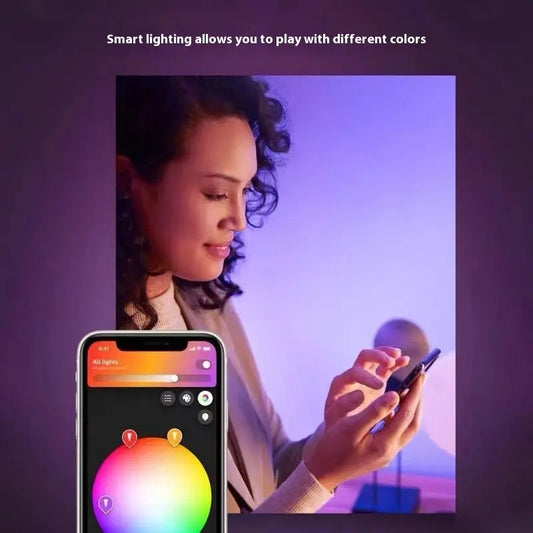 Woman using smartphone app to control color settings on HUE Lightstrip Plus V4 LED ambient lighting strip in room