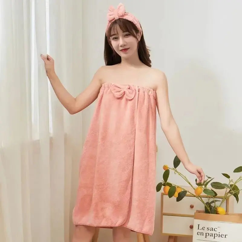 Woman wearing pink microfiber bath towel dress with bow detail and matching headband in bright room