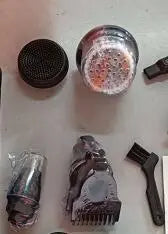 Disassembled 5 in 1 multifunctional electric shaver parts including blade, nose trimmer, and cleaning brush on grey surface