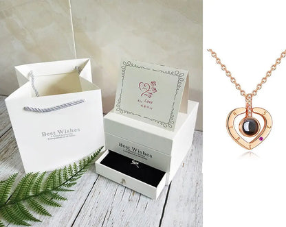 Rose gold heart pendant necklace with black center stone and gift box set with "Best Wishes" card and shopping bag