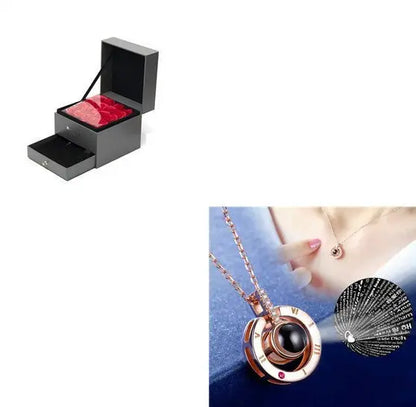 Elegant rose gold necklace with black pendant and projection feature, displayed with black gift box containing red velvet roses
