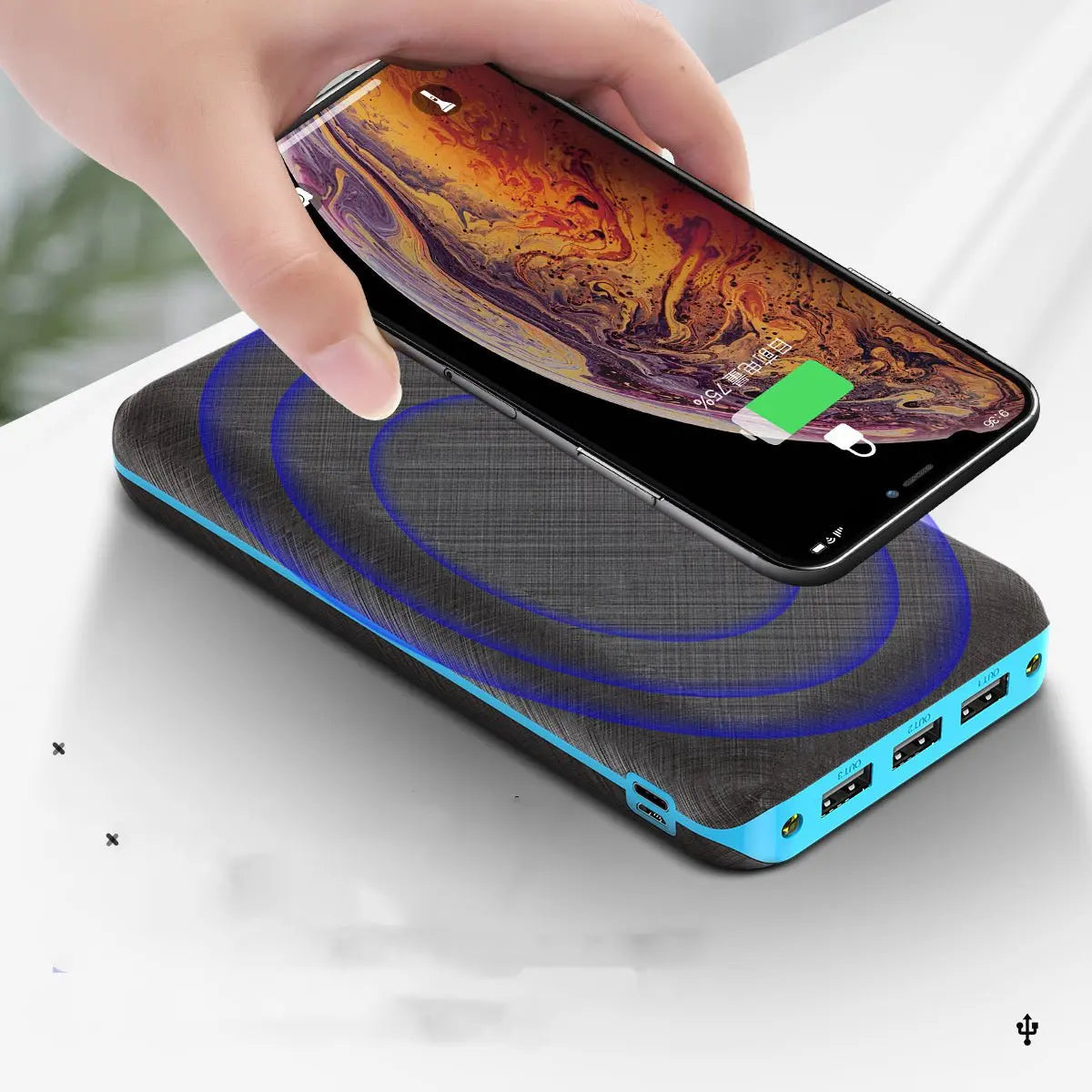 Hand holding smartphone charging wirelessly on portable Qi solar power bank with three USB ports for outdoor use