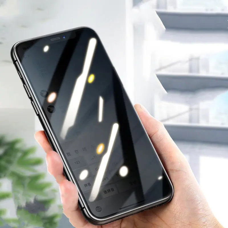 Hand holding iPhone with compatible privacy film showing darkened screen reflecting overhead lights and blurred background