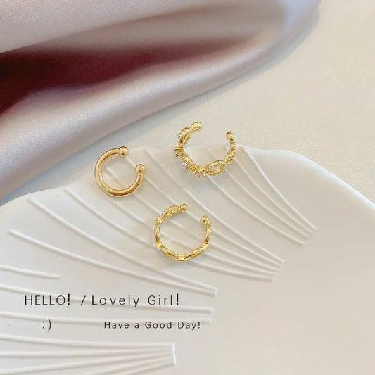 Three gold-toned French retro no pierced ear bone clips with geometric and chain design on white plate