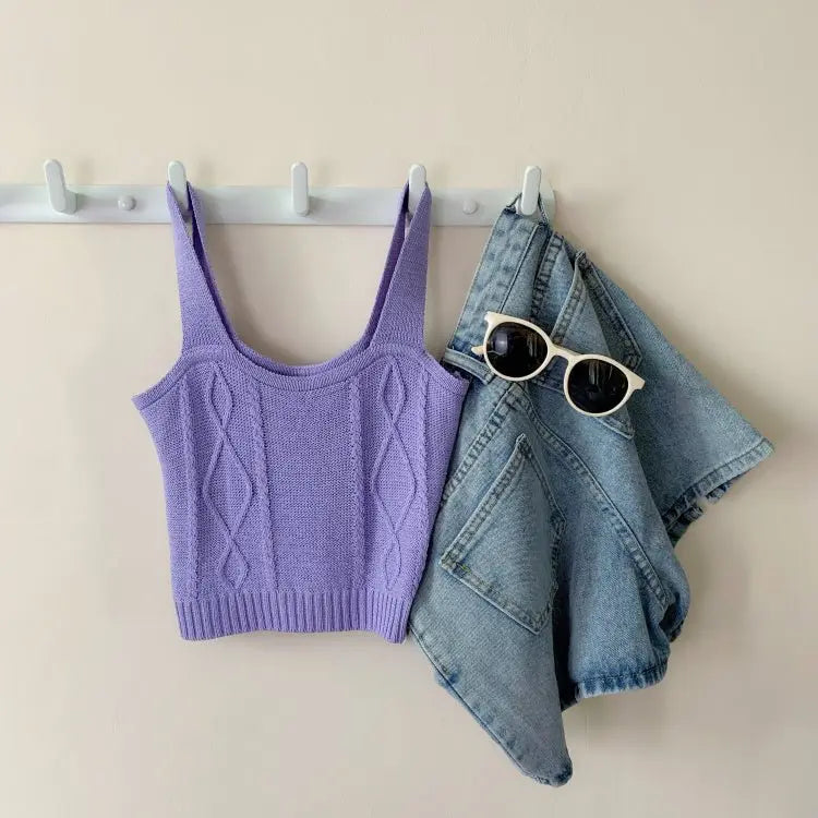 Lilac knitted Hyuna style crop top with cable pattern hanging next to folded blue denim shorts and white round sunglasses