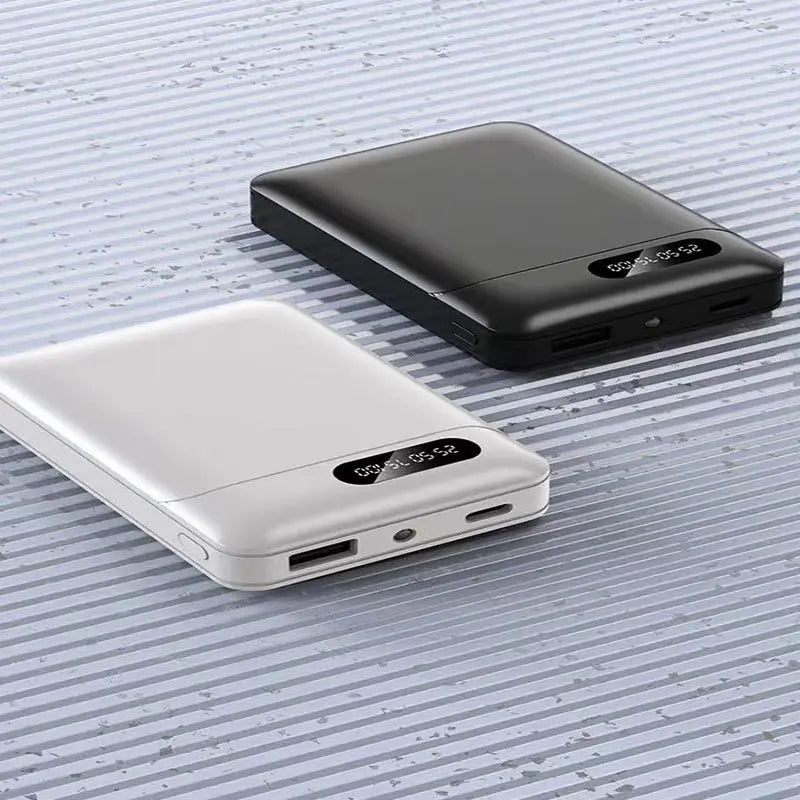 White and black large capacity portable power banks with digital display and multiple charging ports on textured surface