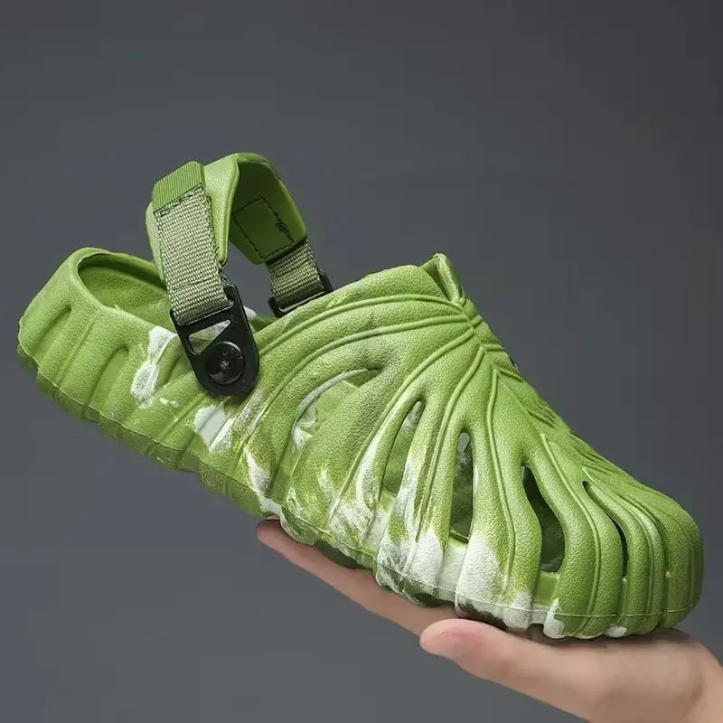 Close-up of green platform slide sandal with adjustable strap and textured Monstera leaf pattern on sole and upper surface