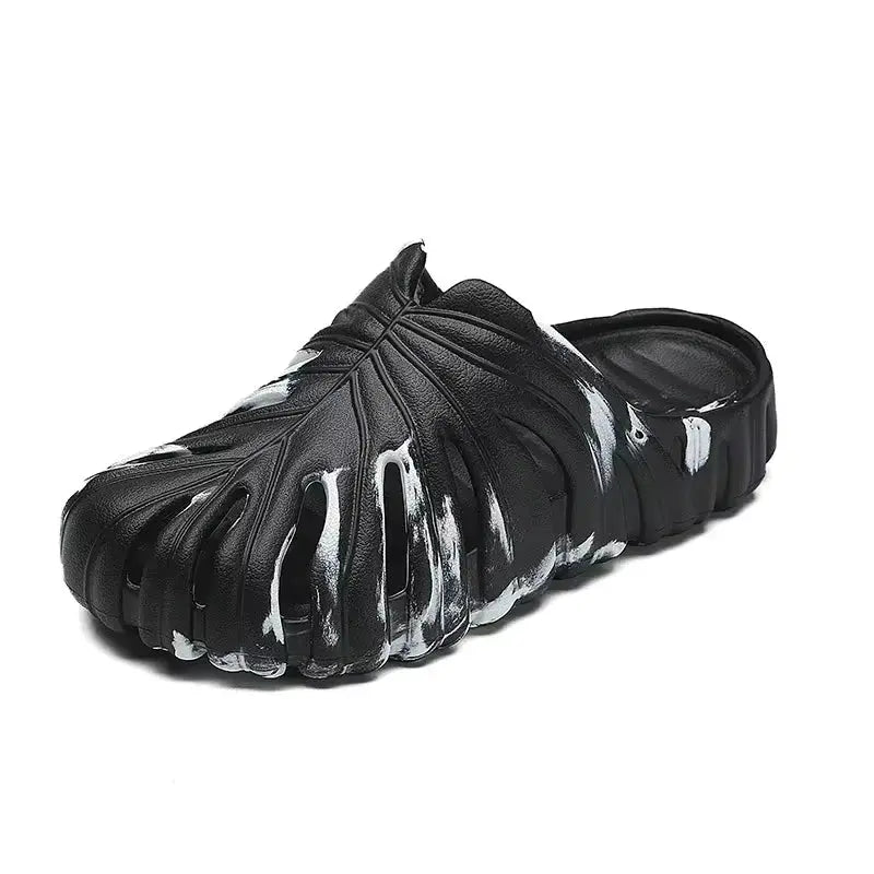 Black slip-on platform slippers with white paint detail, cloud-inspired sole, and textured monstera leaf design