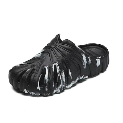 Black slip-on platform slippers with white paint detail, cloud-inspired sole, and textured monstera leaf design