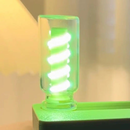 Close-up of mechanical flip flexible night light with glowing spiral lamp inside clear casing on green base