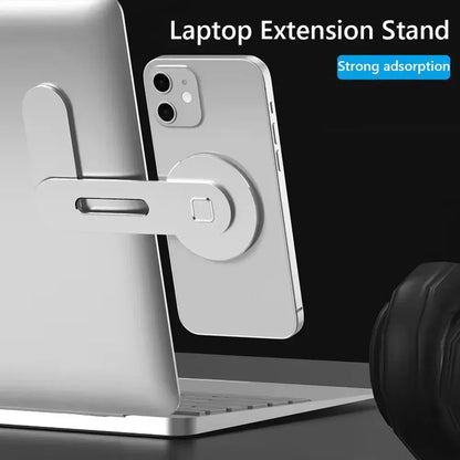 Metal expansion phone stand attached to laptop with adjustable arm holding a silver smartphone magnetically