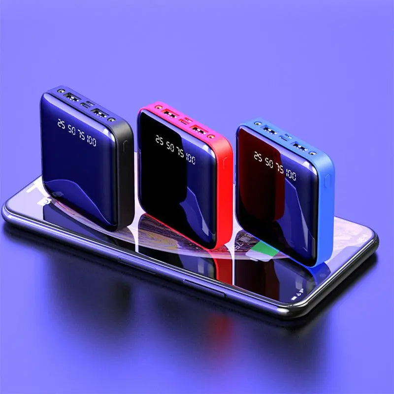 Three Mini Power Bank 20000 mAh portable chargers with mirror digital display in black, red, and blue on smartphone