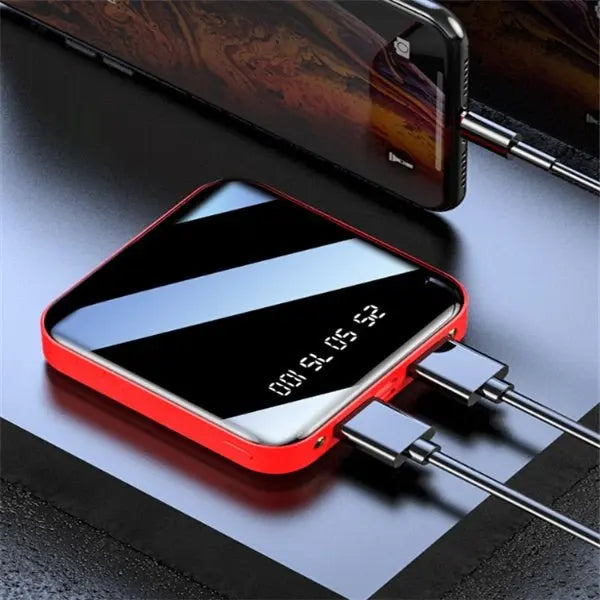Mini portable power bank with 20000 mAh capacity, digital display, red frame, and sleek mirror finish charging two devices