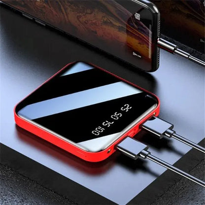Mini portable power bank with 20000 mAh capacity, digital display, red frame, and sleek mirror finish charging two devices