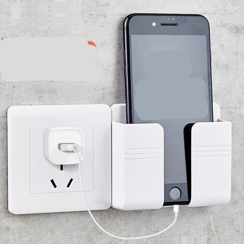 White punch-free sticky storage box mounted on wall holding a charging smartphone beside power outlet