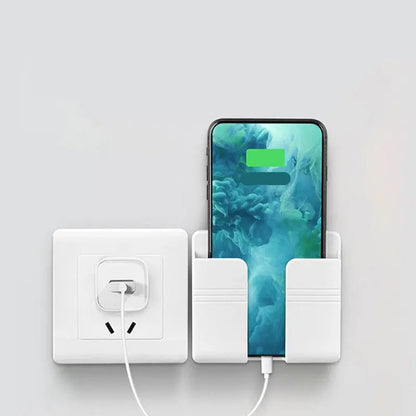 Mobile phone charging storage rack with punch-free adhesive installed next to power outlet holding phone upright