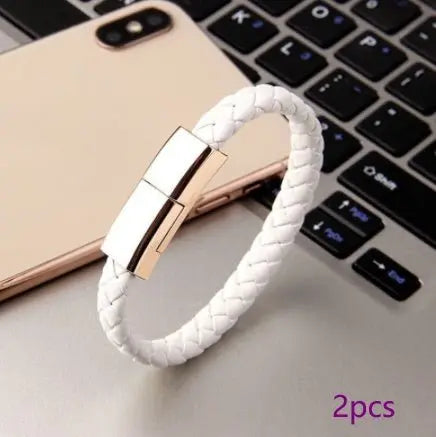 White braided leather bracelet USB charging cable with metallic clasp displayed on laptop keyboard and smartphone background