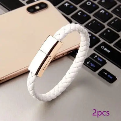 White braided leather bracelet USB charging cable with metallic clasp displayed on laptop keyboard and smartphone background