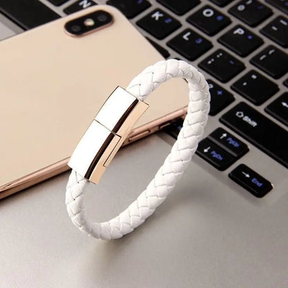 White braided leather bracelet charger with sleek metallic clasp placed on laptop keyboard with smartphones in background