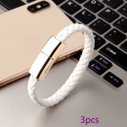 White braided leather bracelet with metallic USB charging connector displayed on laptop keyboard with smartphone nearby