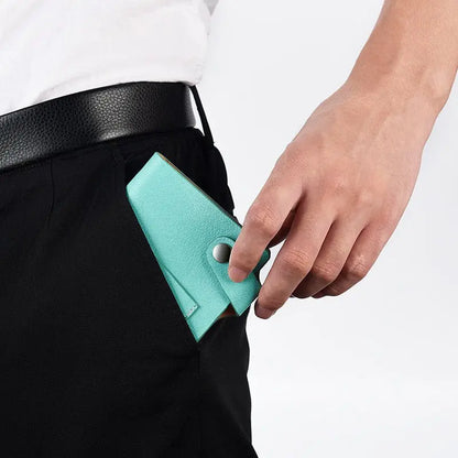Close-up of person’s hand placing turquoise imitation leather repeatable writing paper notebook into black pants pocket