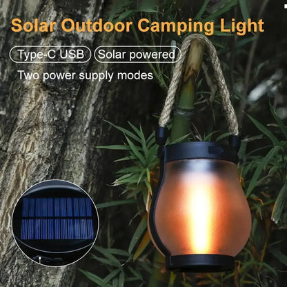 Solar Flame Lamp hanging on tree with glowing light and hemp rope handle for outdoor camping and garden decor