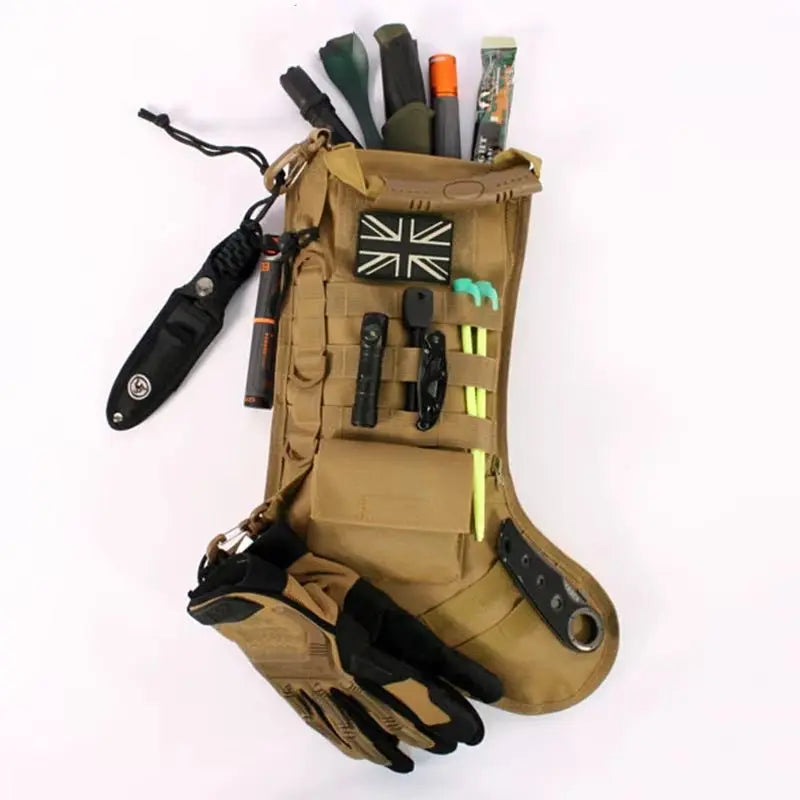 Tan tactical molle Christmas stocking filled with outdoor gear and gloves hanging on white background