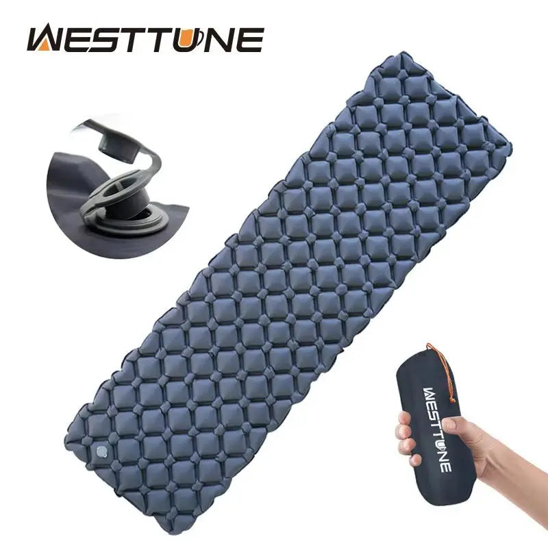 Ultralight inflatable camping sleeping pad in dark blue with honeycomb design and compact carry bag in hand