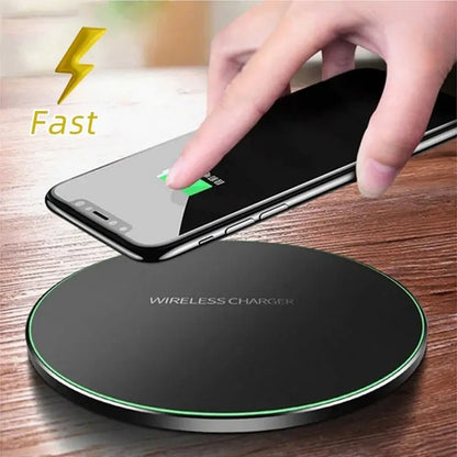 Black round wireless charger pad with green LED ring charging a smartphone placed on wooden surface