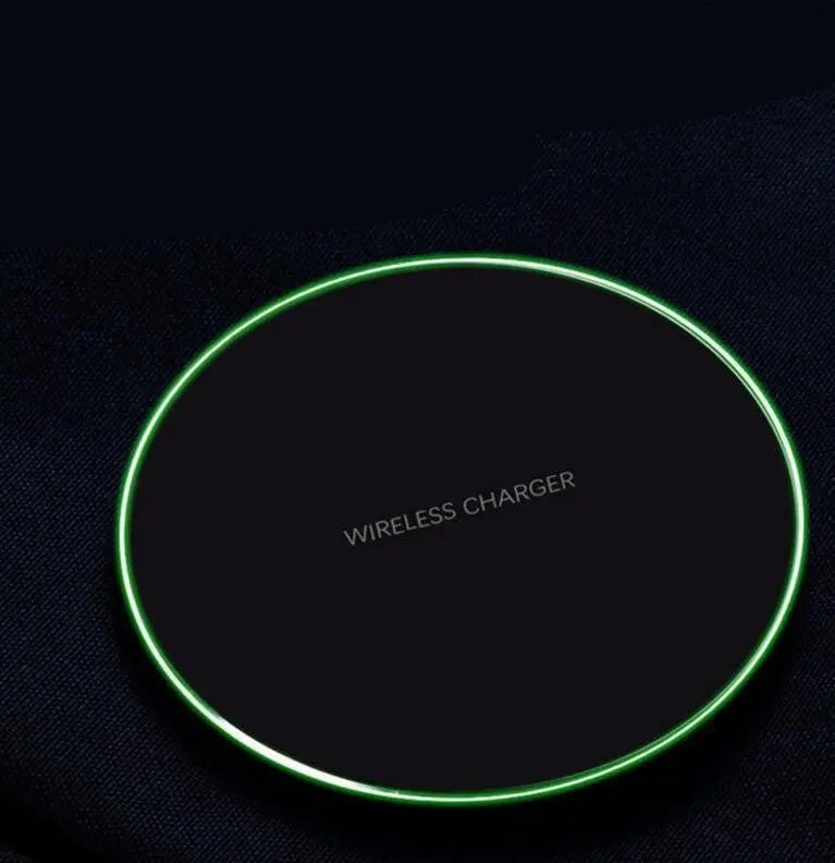 Black round wireless charger pad with glowing green edge and "WIRELESS CHARGER" text in center on dark surface
