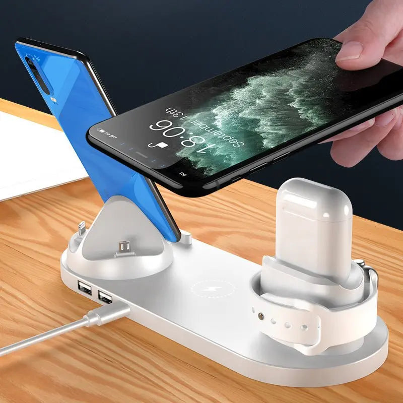 White 6-in-1 wireless charging dock station with phones, wireless earbuds, and smartwatch on wooden surface