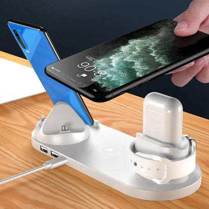 White 6-in-1 wireless charging dock station with phones, wireless earbuds, and smartwatch on wooden surface